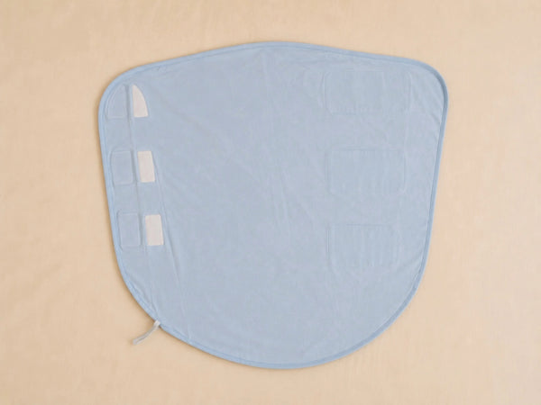 A light blue fabric pad or pad cover with a rounded shape, laid flat on a beige background. It features three white rectangular adhesive patches on one side and a small white zipper tab on the bottom edge.